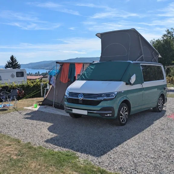Campervan pitched at a campsite overlooking a lake